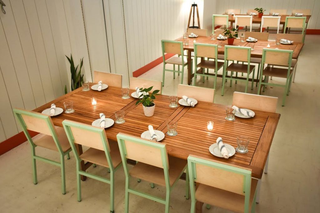 Three brown tables with green accented chairs in a minimalist space