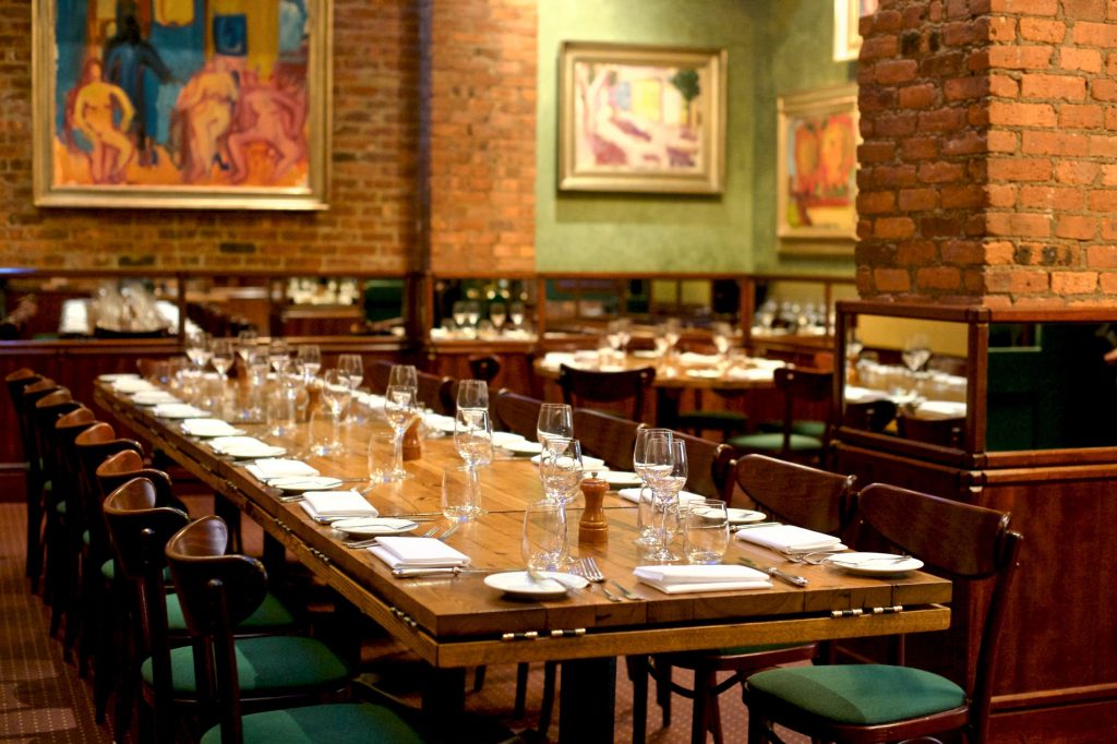 Long wooden table in a room with exposed brick walls and large paintings