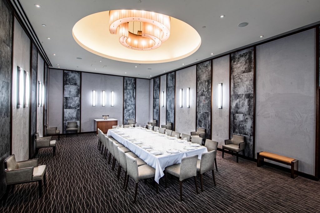 Large Dining room with concrete and marble walls and a long table with white tablecltoh